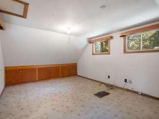 Discover the potential in this attic space, featuring a unique built-in wooden cabinet system perfect for storage.