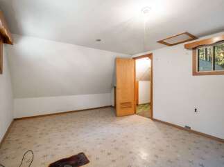 Discover the potential in this charming attic room, featuring a unique starburst patterned carpet and warm wooden accents.