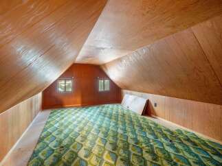 Discover the potential of this attic space, featuring unique sloped wood-paneled ceilings and walls that create a cozy, rustic ambiance.