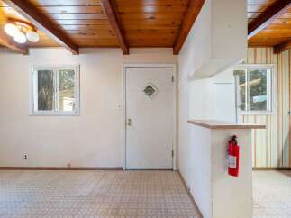 This interior shot showcases a cozy living space with a charming wooden beamed ceiling and a practical layout.