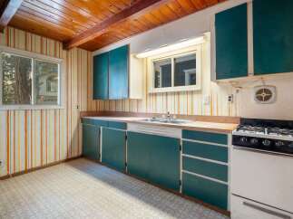 Step into this charming kitchen featuring a rustic wooden beamed ceiling and vibrant striped wallpaper.