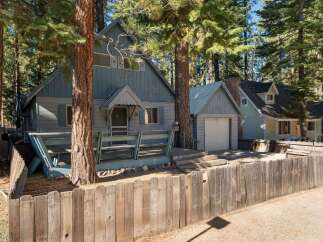 Nestled amongst tall pine trees, this charming blue home offers a rustic retreat.