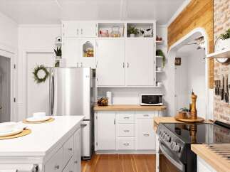 This charming kitchen boasts a farmhouse aesthetic with white cabinetry and a rustic brick accent wall.