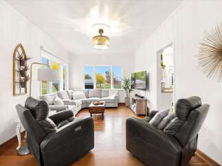 Step into this inviting living room, featuring a spacious sectional sofa perfect for family gatherings and a cozy seating area with plush recliners.