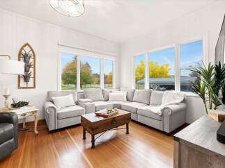 Step into this inviting living room, bathed in natural light from expansive windows showcasing vibrant autumn foliage.