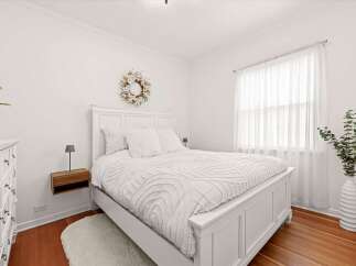 Experience serene comfort in this beautifully appointed bedroom, featuring a plush white bed adorned with textured bedding and fluffy pillows.