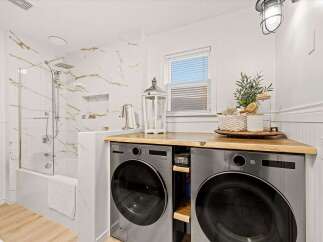 This modern laundry room features a sleek LG washer and dryer set neatly tucked under a beautiful butcher block countertop.