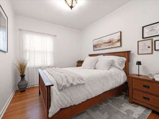 This inviting bedroom features a warm wooden bed frame complemented by crisp white bedding and plush throws, creating a cozy and serene atmosphere.