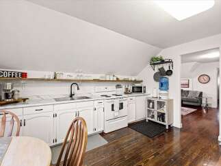 Charming kitchen featuring white cabinetry, marble countertops, and a sleek black faucet.
