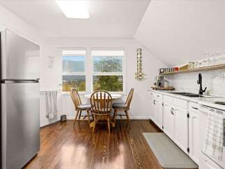 This charming kitchen boasts a cozy dining nook with a round table and three wooden chairs, perfect for intimate meals.