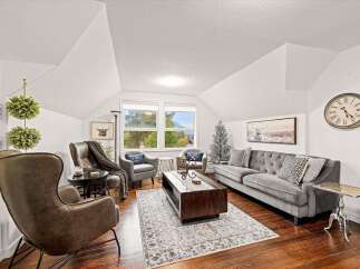 Step into this inviting living room, featuring a plush gray tufted sofa adorned with decorative pillows and a large area rug.