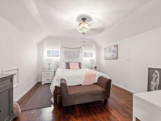 This charming bedroom features a comfortable queen-size bed with plush bedding and decorative pillows, creating a cozy retreat.