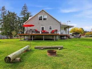 Enjoy outdoor living with a spacious deck featuring a red umbrella and comfortable seating, perfect for entertaining.