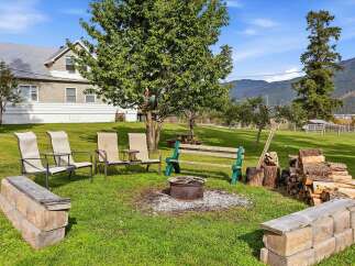 Enjoy outdoor living with this charming fire pit area, complete with comfortable seating and a stack of firewood ready for use.