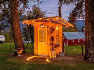 Experience rustic charm with this unique wooden structure, illuminated by festive string lights and pathway candles.