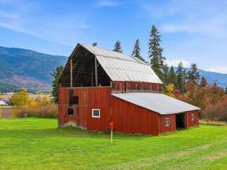 Experience rustic charm with this classic red barn, set against a backdrop of rolling hills and vibrant autumn foliage.
