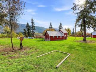 Experience rural charm with this picturesque property featuring a classic red barn and expansive green fields.