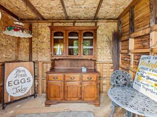 This charming rustic space features a vintage wooden hutch and a quaint 'Farm Fresh Eggs Today' sign, evoking a cozy, country feel.