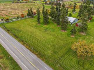 Discover this charming rural property featuring a classic red barn and a spacious metal-roofed outbuilding, perfect for storage or agricultural use.