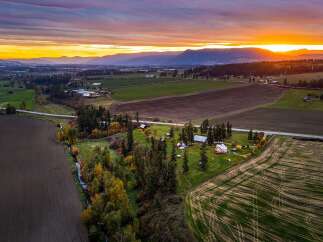 Experience the beauty of rural living with this stunning aerial view of a farm at sunset.