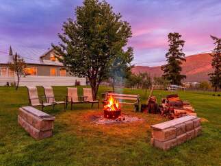 Experience the perfect evening ambiance with a crackling fire pit, surrounded by comfortable seating and a scenic mountain backdrop.