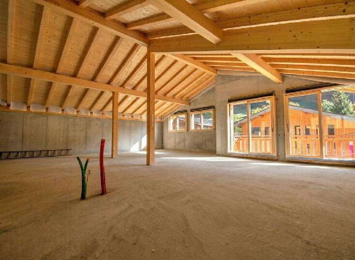 Discover this spacious, unfinished interior with a stunning exposed wooden beam ceiling and concrete walls, offering a blank canvas for your dream home.
