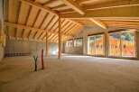 Discover this spacious, unfinished interior with a stunning exposed wooden beam ceiling and concrete walls, offering a blank canvas for your dream home.