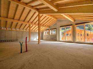 Discover this spacious, unfinished interior with a stunning exposed wooden beam ceiling and concrete walls, offering a blank canvas for your dream home.