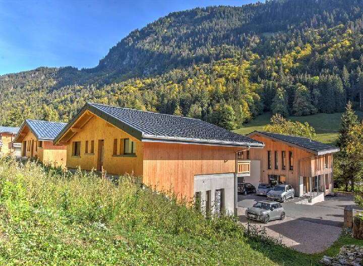 Experience the charm of alpine living in these modern wooden chalets, nestled against a backdrop of lush green mountainside.