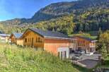 Experience the charm of alpine living in these modern wooden chalets, nestled against a backdrop of lush green mountainside.