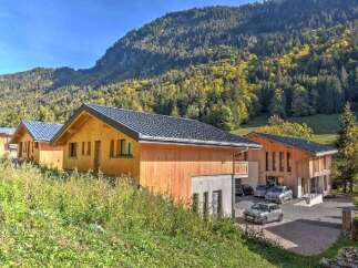 Experience the charm of alpine living in these modern wooden chalets, nestled against a backdrop of lush green mountainside.