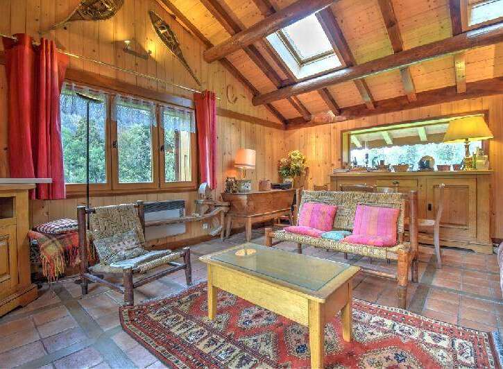 Experience rustic charm in this cozy living room, featuring warm wood paneling and exposed beams.