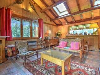 Experience rustic charm in this cozy living room, featuring warm wood paneling and exposed beams.
