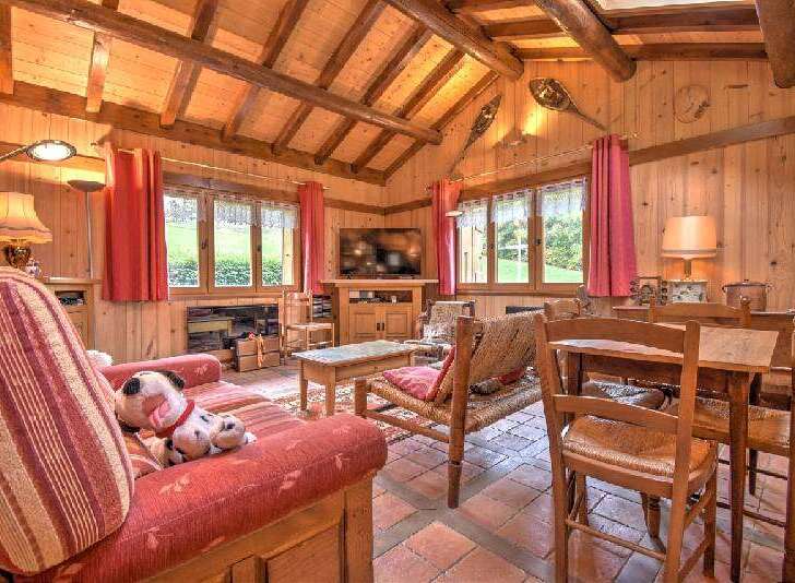 Experience rustic charm in this cozy living room, featuring exposed wooden beams and warm wood-paneled walls.