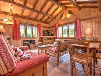 Experience rustic charm in this cozy living room, featuring exposed wooden beams and warm wood-paneled walls.