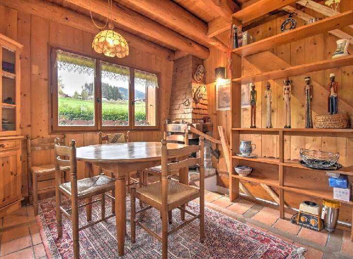 Experience rustic charm in this cozy dining area, featuring a wooden table and chairs set against a backdrop of natural wood walls and exposed beams.