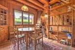 Experience rustic charm in this cozy dining area, featuring a wooden table and chairs set against a backdrop of natural wood walls and exposed beams.