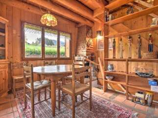 Experience rustic charm in this cozy dining area, featuring a wooden table and chairs set against a backdrop of natural wood walls and exposed beams.