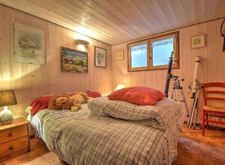 Cozy wooden paneled bedroom featuring a comfortable bed with plaid bedding and plush toys.