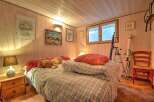 Cozy wooden paneled bedroom featuring a comfortable bed with plaid bedding and plush toys.