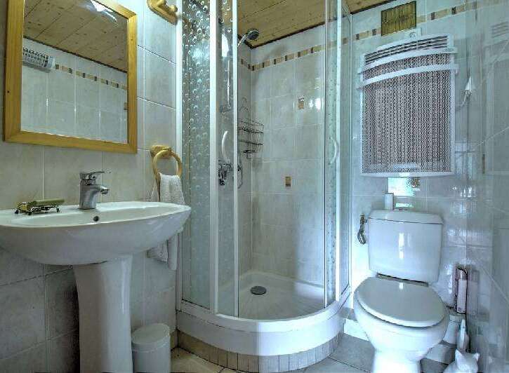 This compact bathroom features a modern pedestal sink with a chrome faucet and a wooden-framed mirror above.