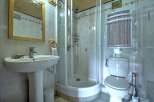 This compact bathroom features a modern pedestal sink with a chrome faucet and a wooden-framed mirror above.