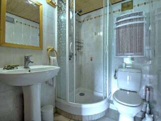 This compact bathroom features a modern pedestal sink with a chrome faucet and a wooden-framed mirror above.