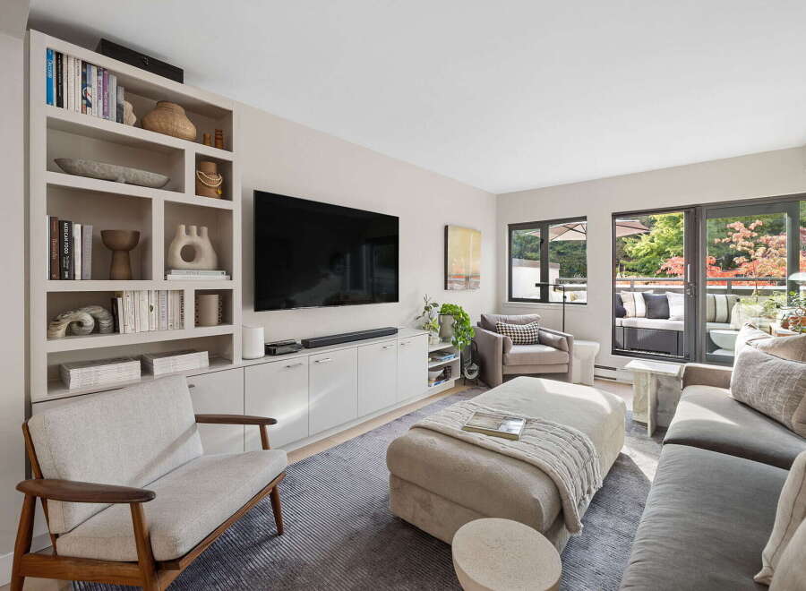 This modern living room features a large built-in bookshelf filled with decorative items and books, complementing the sleek entertainment center and wall-mounted TV.