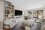 This modern living room features a large built-in bookshelf filled with decorative items and books, complementing the sleek entertainment center and wall-mounted TV.