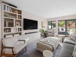 This modern living room features a large built-in bookshelf filled with decorative items and books, complementing the sleek entertainment center and wall-mounted TV.