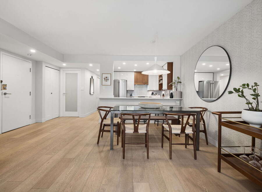 Step into this beautifully appointed dining area, featuring a sleek glass-top dining table with modern wooden chairs, perfect for intimate gatherings.