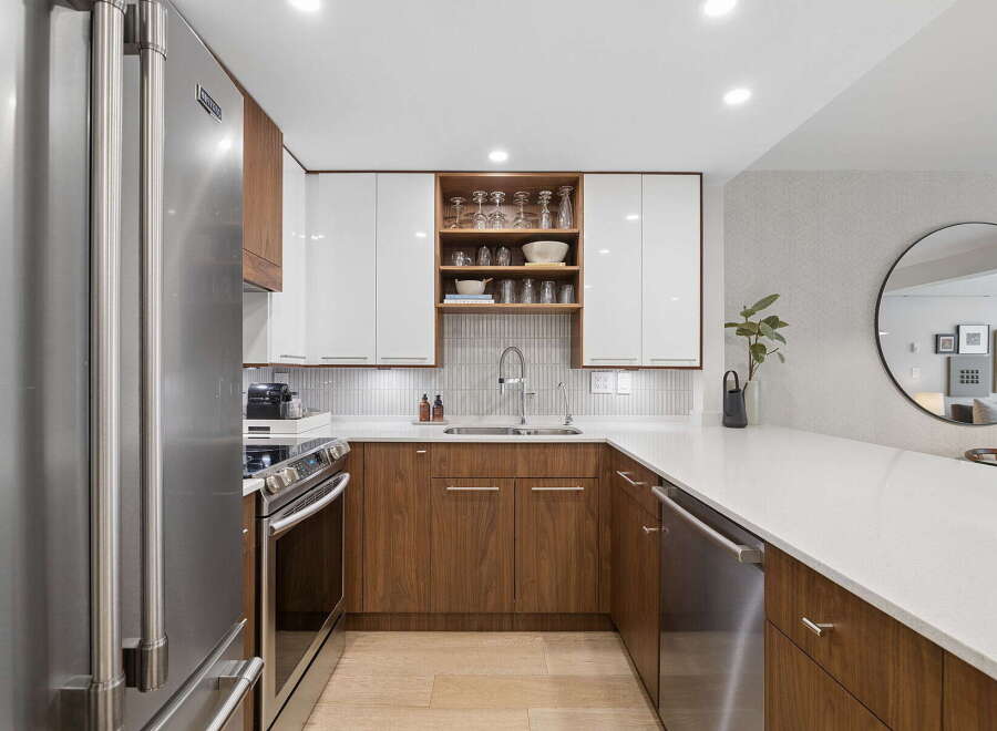 Experience modern living in this sleek kitchen, featuring high-gloss white cabinetry contrasted with warm walnut lower cabinets.
