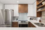Experience modern luxury in this stunning kitchen, featuring sleek white cabinetry and warm wood accents.