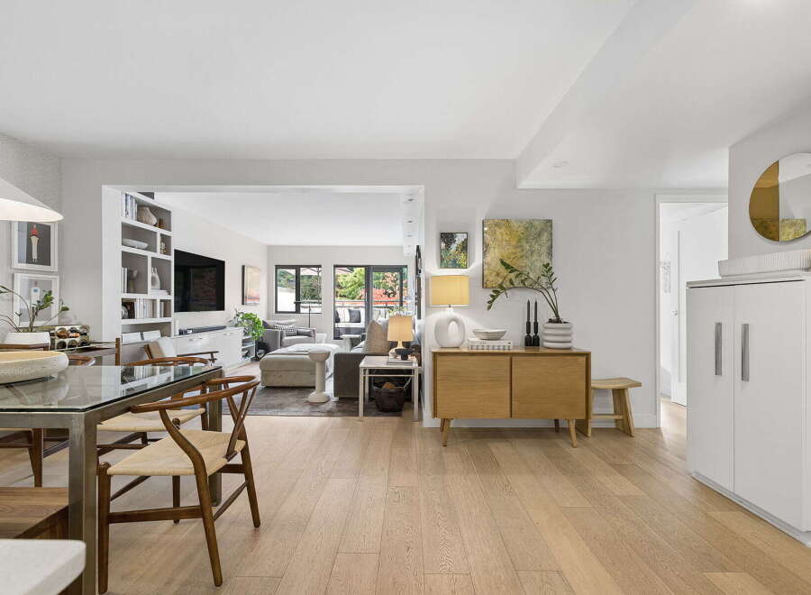 Discover modern living in this beautifully appointed open-concept space, featuring a sleek dining area with a glass-top table and comfortable wishbone chairs.